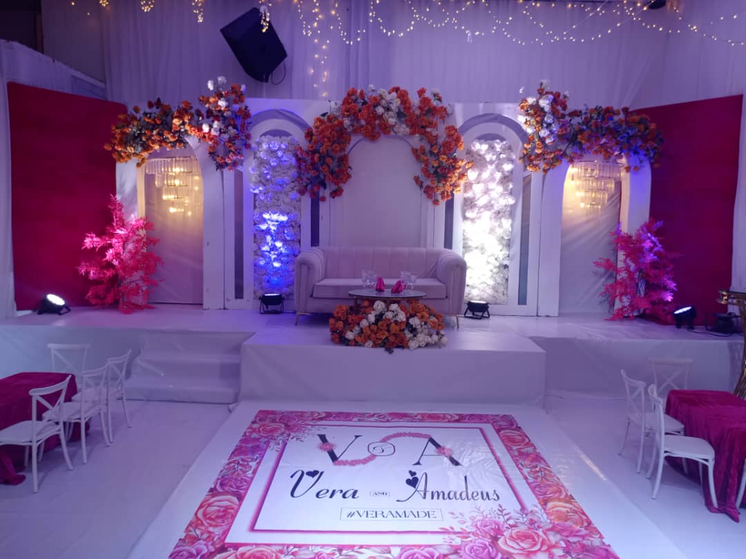 Scène de mariage avec arches florales, fond de scène tendu et espace lounge
