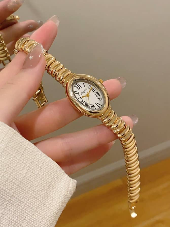 Montre femme dorée à cadran ovale et bracelet segmenté façon ressort